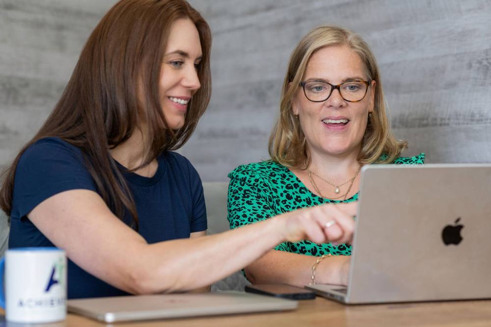 Cathrin Westerwelle and Camilla Arntsen of Achieve CTC working together at a laptop
